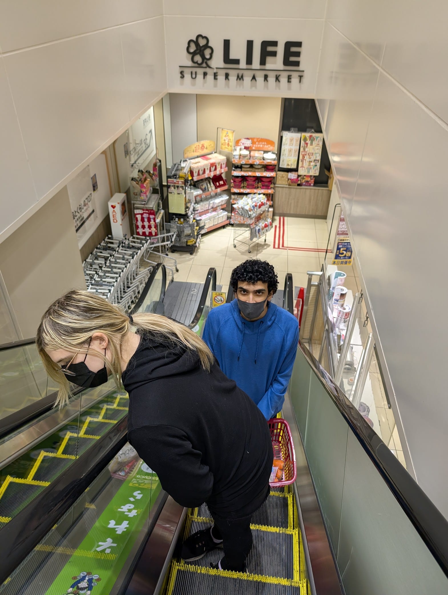 Vivi and Cardia on an escalator in the grocery store