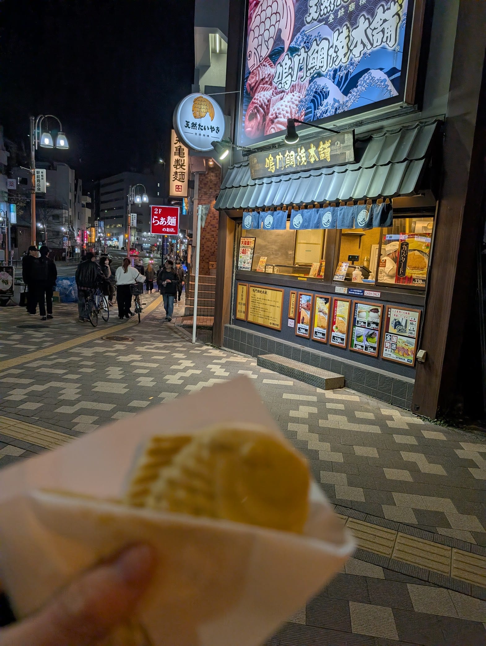 POV holding taiyaki in front of the store