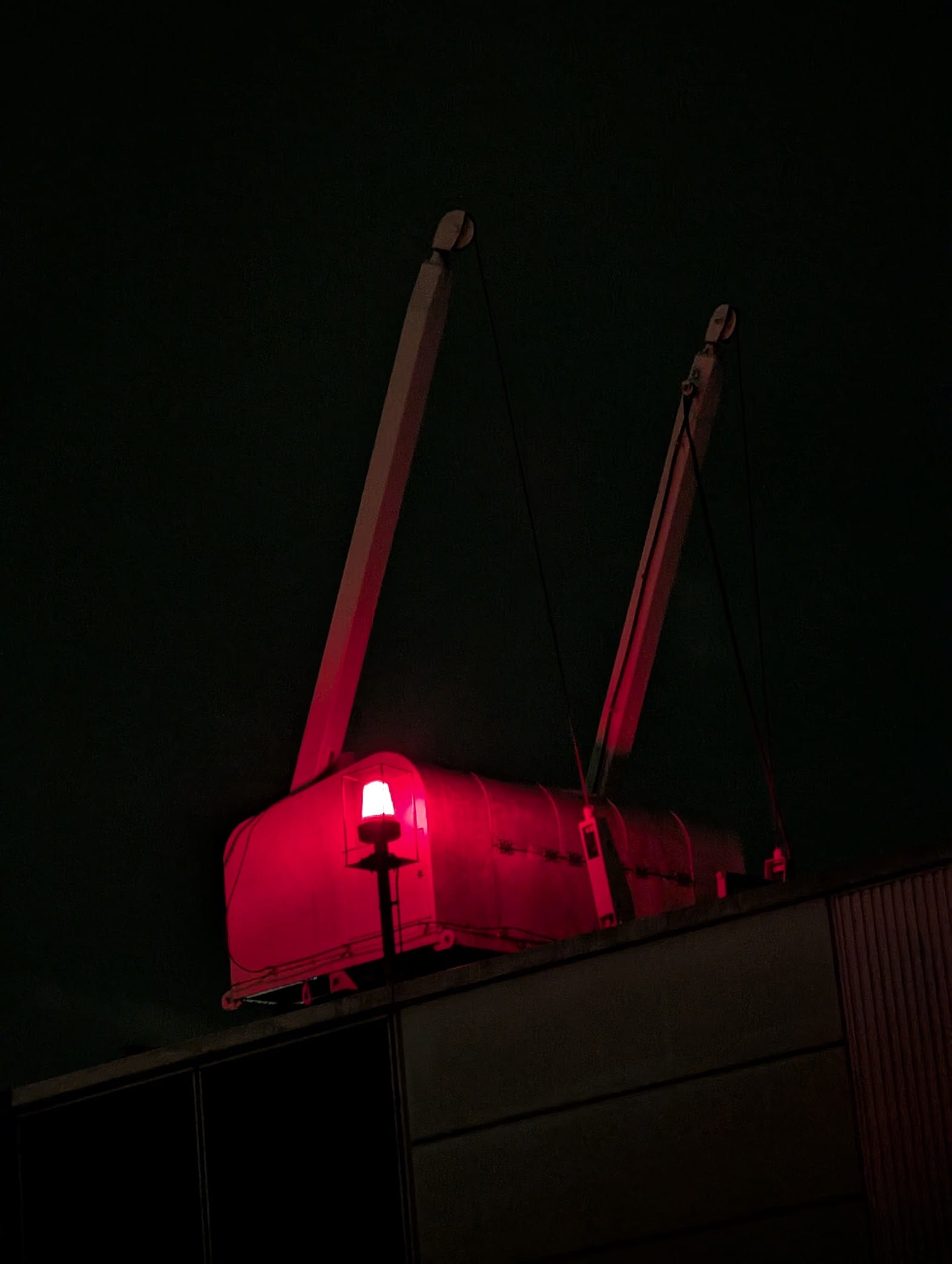 A red point light illuminating the side of something on the roof