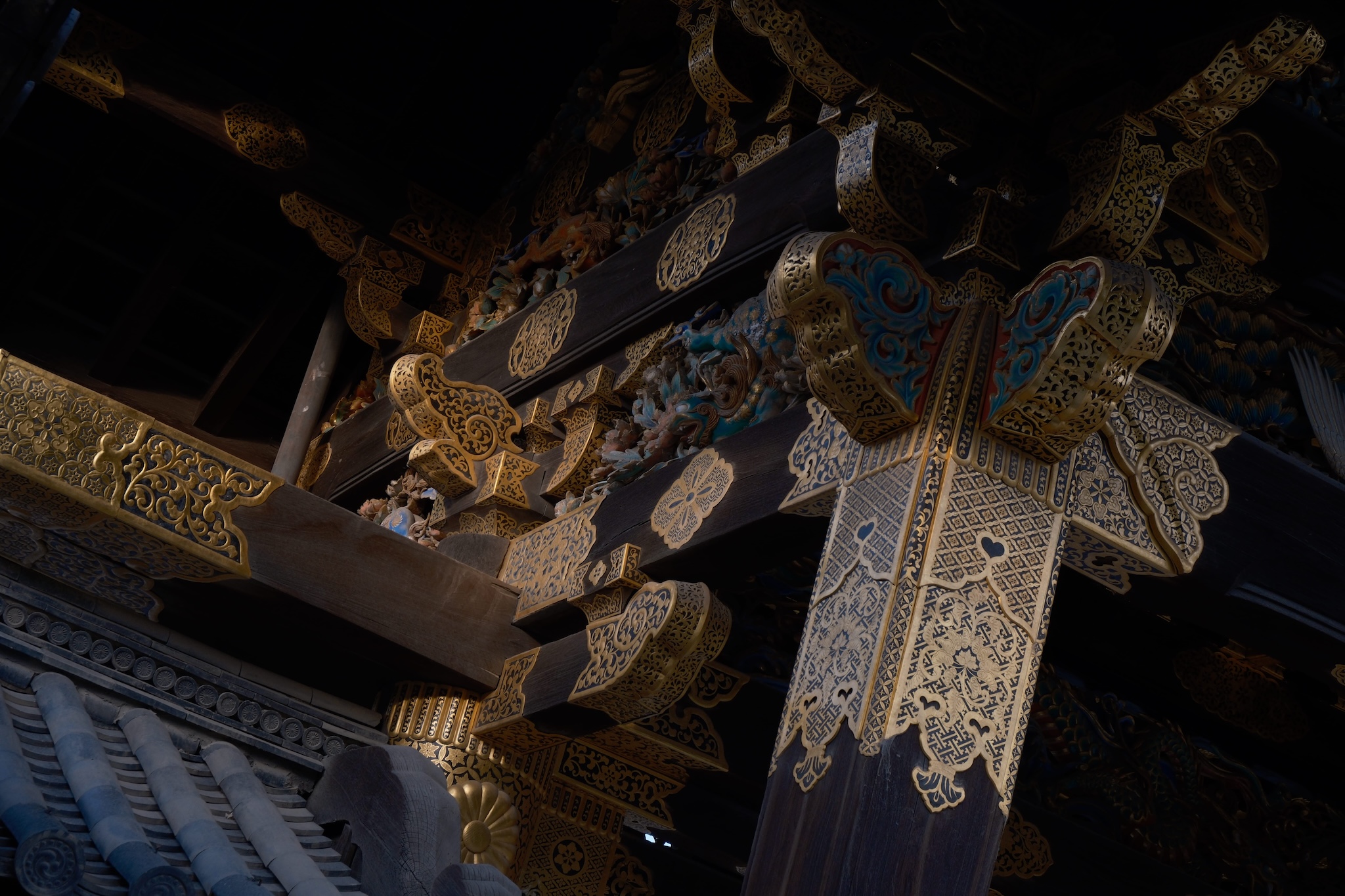The golden ornamentation on the supports of a gate to Nijo Castle in moody lighting